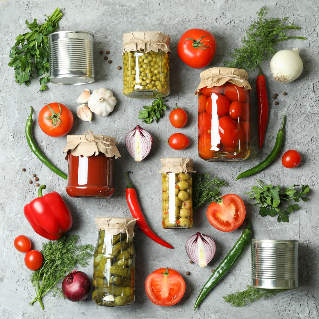 Flat lay with different canned food and ingredients on gray background
